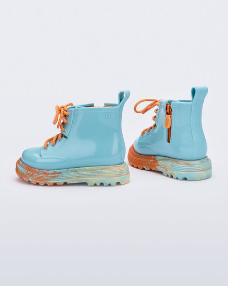 Back and side view of a pair of blue Coturno baby boots with orange laces.