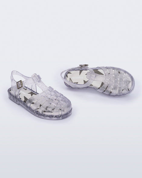 Angled view of a pair of clear Possession kids sandals with star glitter