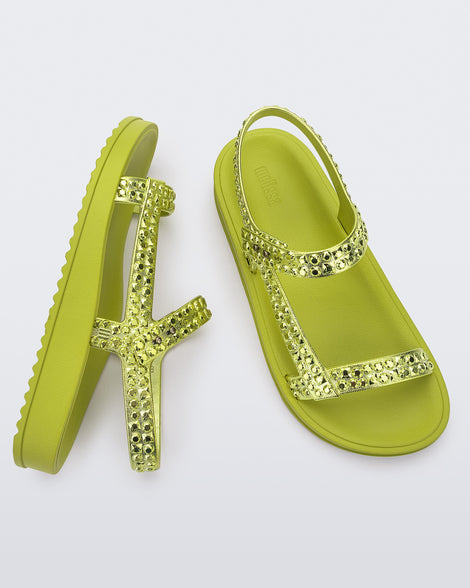 Side and top view of a pair of green Lust sandals with metallic green strap