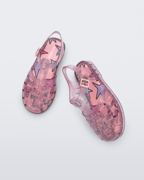 Angled and top view of a pair of clear pink Possession kids sandals with star glitter