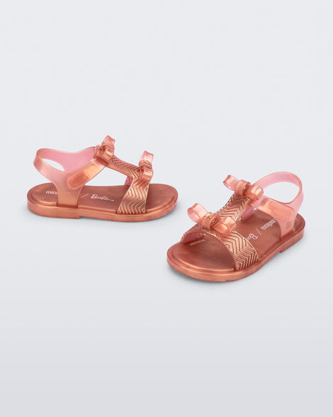 Side and angled view of a pair of pink baby Dream Sandal with two bows and gold detail on strap