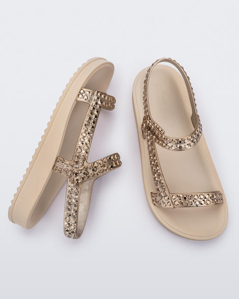 Side and top view of a pair of beige Lust sandals with gold strap