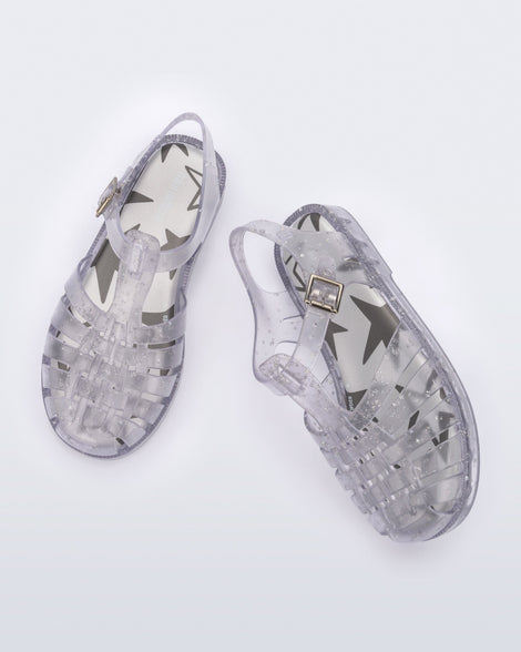 Angled and top view of a pair of clear Possession kids sandals with star glitter