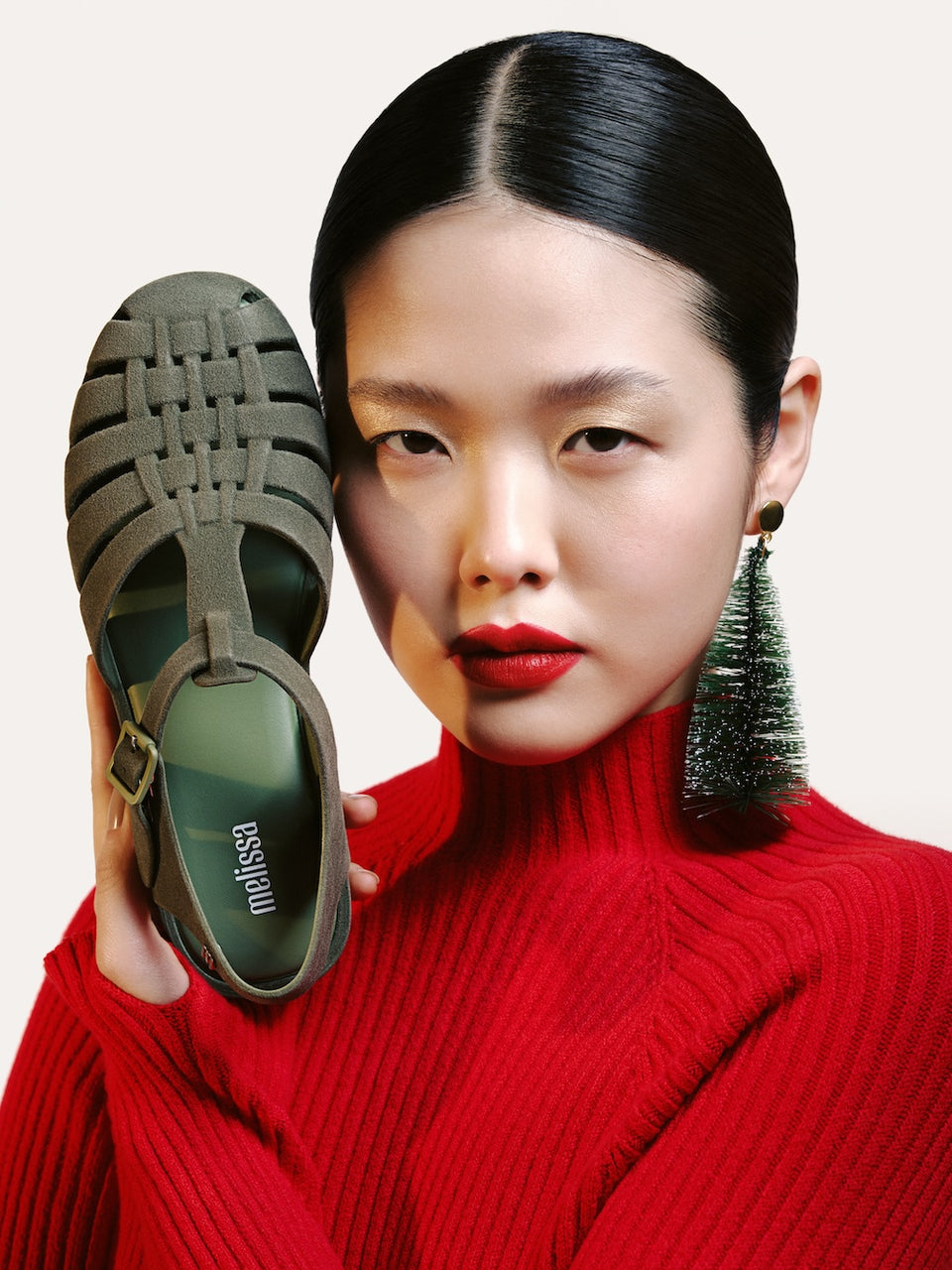 model holding the green possession velvet sandal