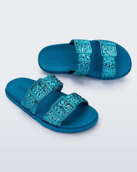 Top and angled view of a pair of blue Lust Slide with metallic buckle straps