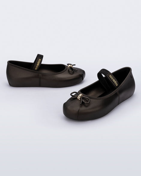 Side and angled view of a pair of metallic black Sophie kids ballerina flats with bow