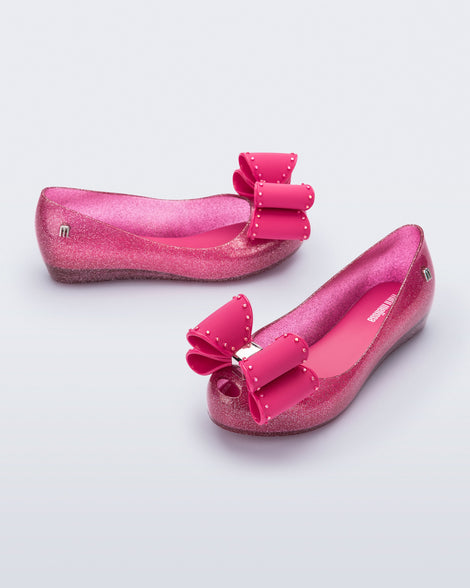 Angled view of a pair of glitter pink kids Ultragirl Classic Bow kids flats