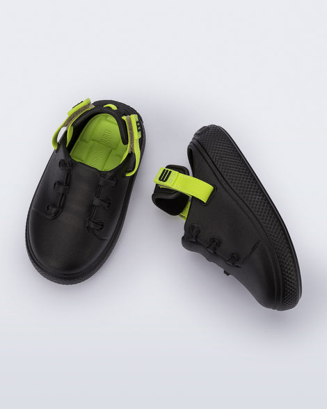 Side and top view of a pair of black with green back strap Charlie baby sneakers