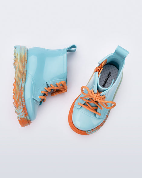 Top and side view of a pair of blue Coturno baby boots with orange laces.