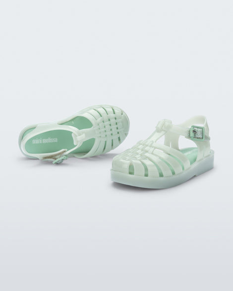 Top and side view of a pair of light green baby Possession sandals.
