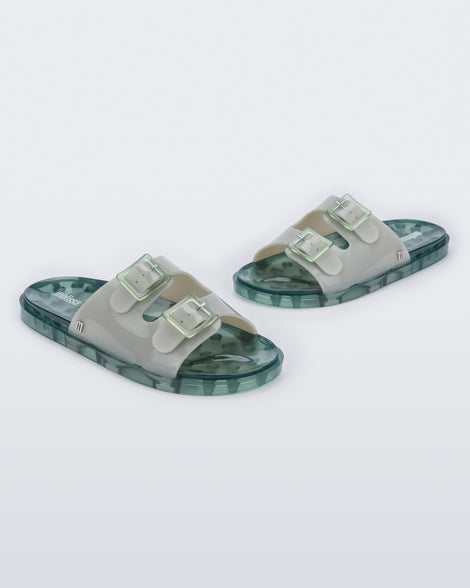 Angled view of a pair of Melissa Wide slide sandals with green sole and two grey/green front straps