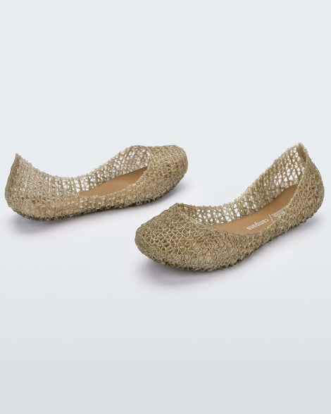 An angled side and back view of a pair of gold glitter Mini Melissa Campana flats with a woven detail base.