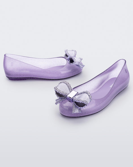 Side and angled view of a pair of lilac Mini Melissa Sweet Love kids flats with metallic lilac bow.