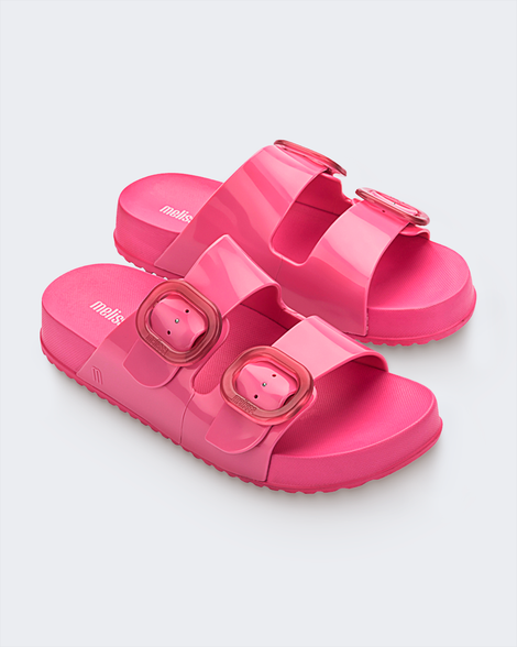 An angled side view of a pair of pink Melissa Cozy slides