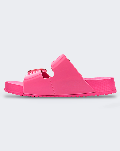 An inner side view of a pink Melissa Cozy slide on a gray background