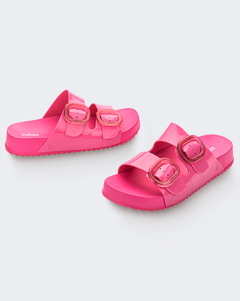 An angled front and side view of a pair of pink Melissa Cozy slides