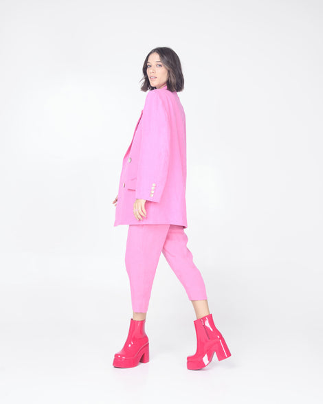 A model in pink capris and pink blazer wearing a pair of pink Melissa Nubia platform heel boots.