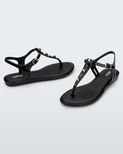 Angled and side view of a pair of black Melissa Solar studs sandals with gold studded t-strap and gold buckle.
