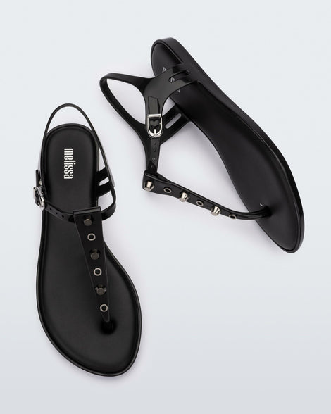 Top and side view of a pair of black Melissa Solar studs sandals with gold studded t-strap and gold buckle.
