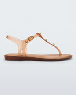 Side view of a clear beige Melissa Solar studs sandal with gold studded t-strap and gold buckle.
