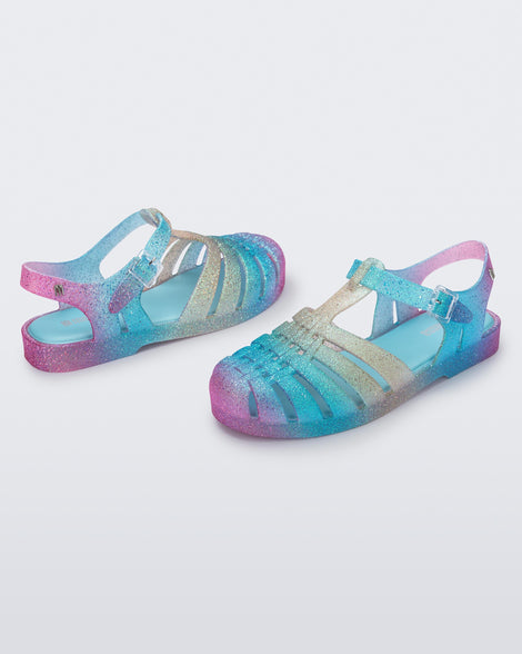 Angled view of a pair of blue and pink glitter Possession sandals.