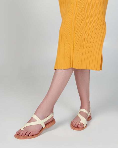 Model's leg's in an orange dress wearing a pair of beige Cassie sandals