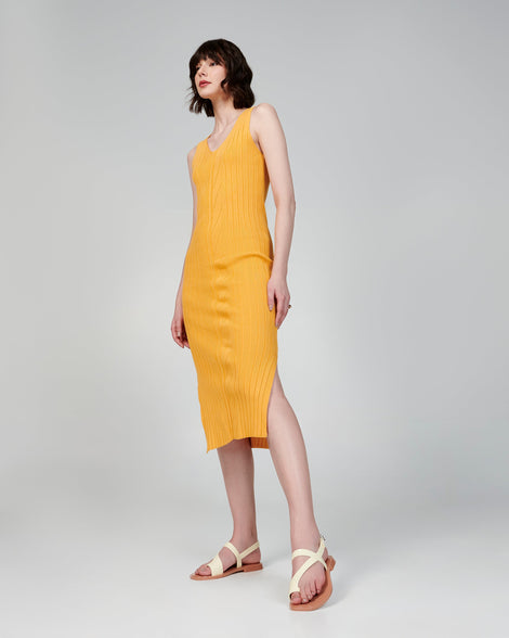 Model in an orange dress wearing a pair of beige Cassie sandals