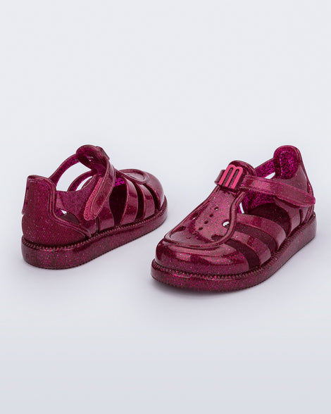 Back and angled view of a pair of glitter pink baby Hip Daydream sandals