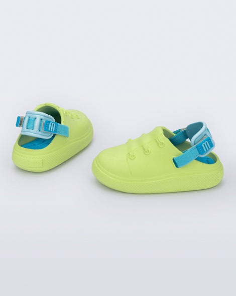 Side and back view of a pair of green with blue back strap Charlie baby sneakers