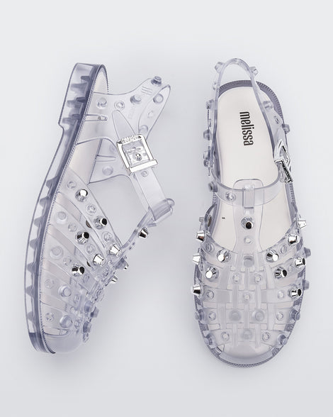 Side and top view of a pair of clear Possession Studs fisherman sandals with silver studs.