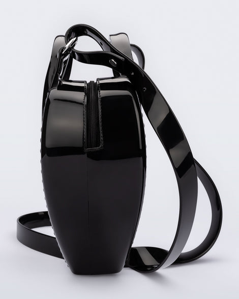 Side view of a black Heartbeat bag with small handles and longer strap.