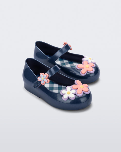 Angled view of a pair of metallic blue Sweet Love Picnic baby flats with flowers