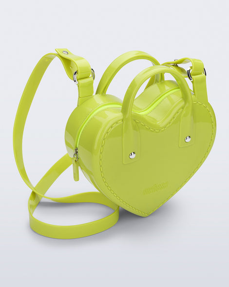 Angled view of a green Heartbeat bag with small handles and longer strap.