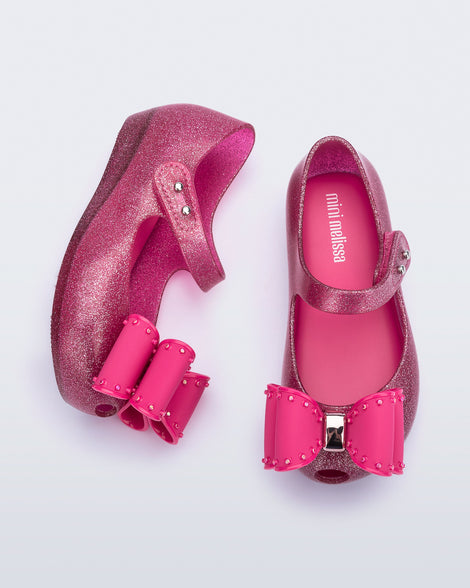 Top and side view of a pair of glitter pink baby Ultragirl Classic Bow flats