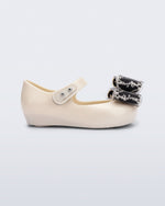 Side view of a beige baby Ultragirl Classic Bow flats with black and clear bow