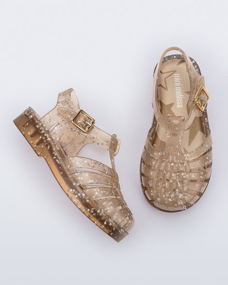 Side and top view of a pair of clear beige Possession baby sandals with star glitter