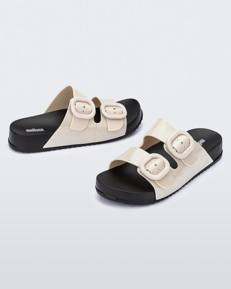 Angled view of a pair of black sole with beige upper Cozy slides.