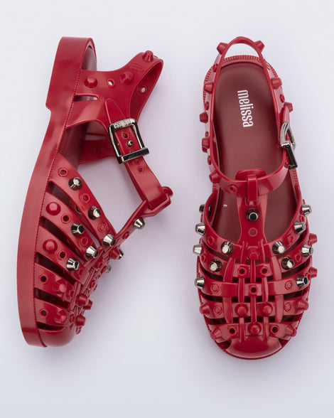 Side and top view of a pair of red Possession Studs fisherman sandals with silver studs.