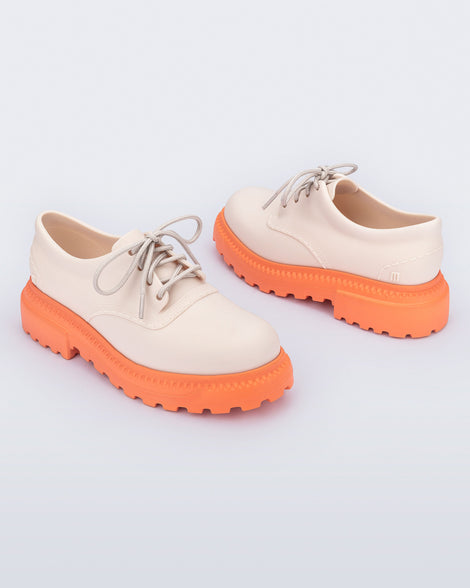 Angled view of a pair of beige with orange sole Charlotte adult sneaker loafers with laces