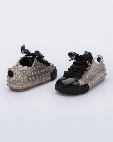 Back and angled view of a pair of clear glitter Polibolha baby sneakers with black laces.