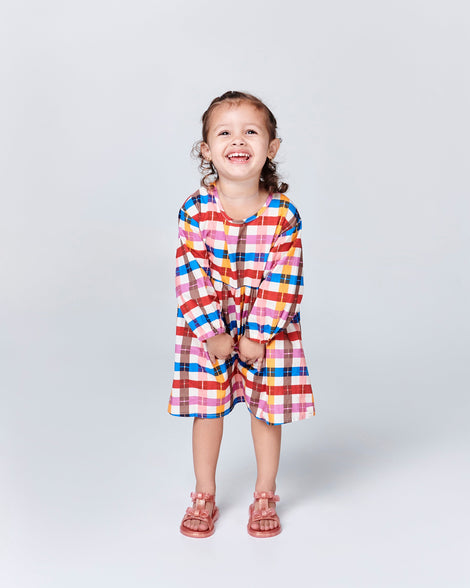 Child model in a white patterned dress wearing a pair of pink baby Dream sandals