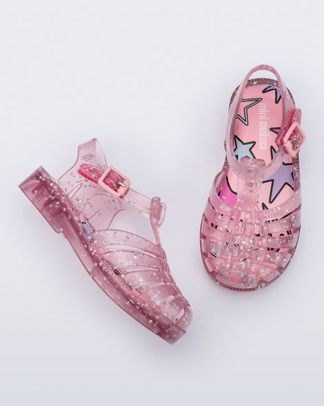 Side and top view of a pair of clear pink Possession baby sandals with star glitter