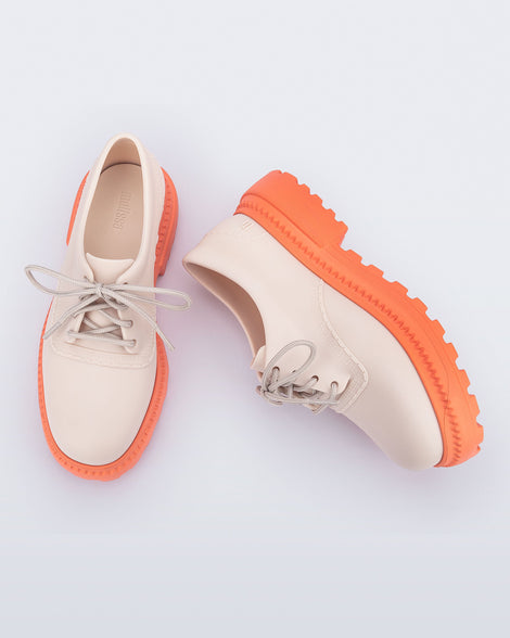 Top and side view of a pair of beige with orange sole Charlotte adult sneaker loafers with laces