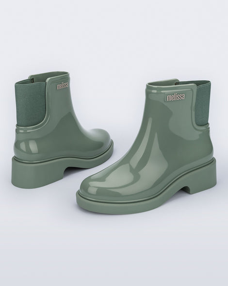 Back and angled view of a pair of sage green Chelsea Boots.