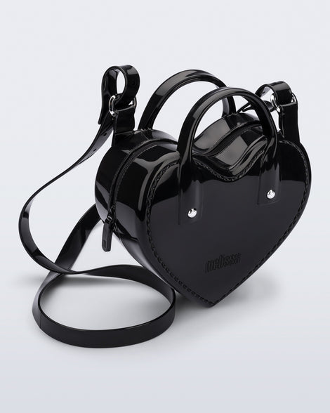 Angled view of a black Heartbeat bag with small handles and longer strap.