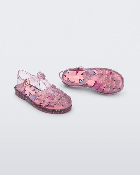 Angled view of a pair of clear pink Possession kids sandals with star glitter