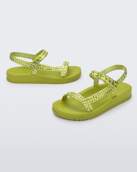 Side and angled view of a pair of green Lust sandals with metallic green strap