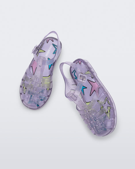 Angled and top view of a pair of clear lilac Possession kids sandals with star glitter