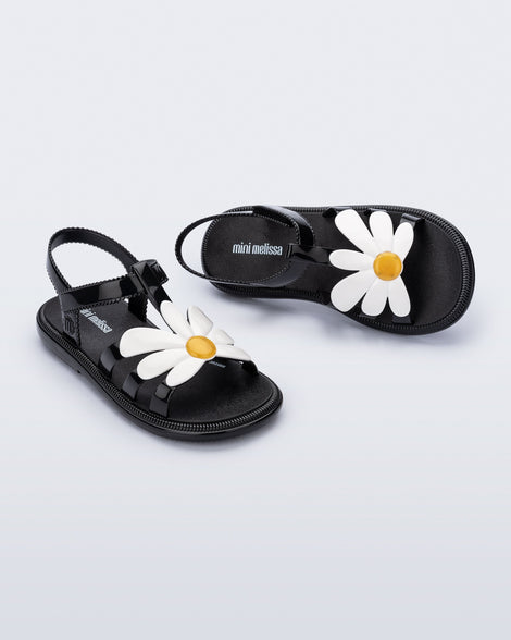 Angled view of a pair of black and white kids Hip Bloomy sandal.