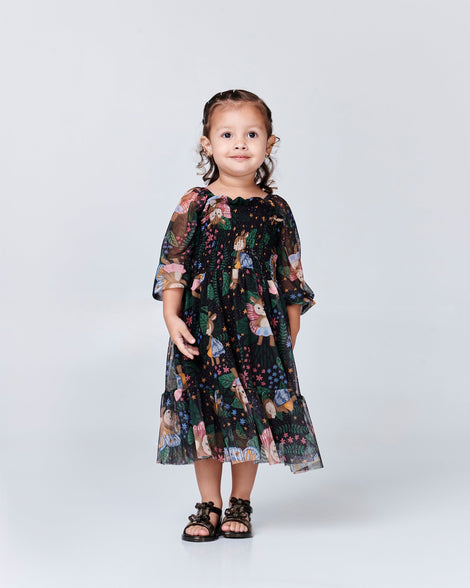 Child model in a black patterned dress wearing a pair of black baby Dream sandals